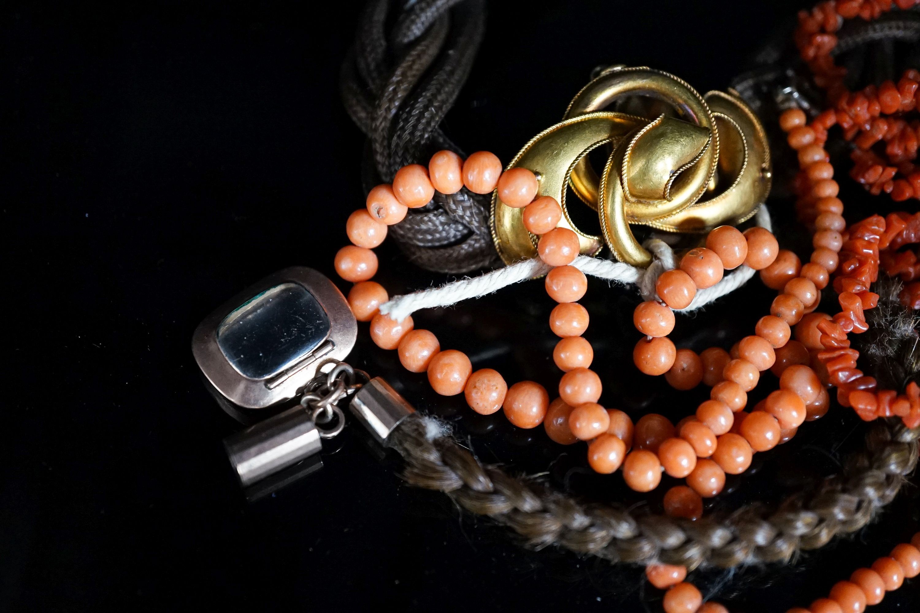 A Victorian yellow metal mounted hairwork bracelet, hung with plaited hair tassel with yellow metal fob, and two coral necklaces.